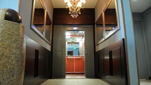 A hallway with a chandelier, mirrored walls, and a reception area at the end. - Hotel Sarah Nui (Papeete)