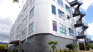 A modern hotel with a curved facade, multiple windows, and a spiral staircase on the right side. - Hotel Sarah Nui (Papeete)
