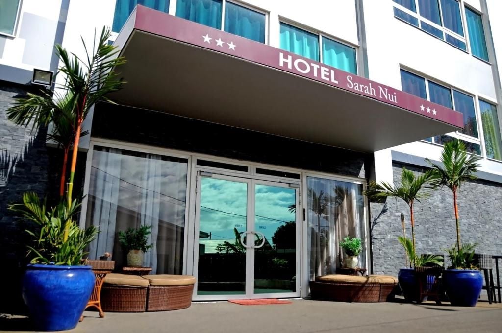 Entrada de un hotel con un letrero que dice 'HOTEL Sarah Nui' y una puerta de vidrio.