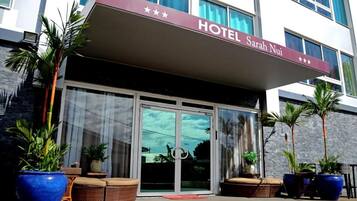 Ein Hotel Eingang mit einem Schild mit der Aufschrift 'HOTEL Sarah Nui' und einer Glastür.