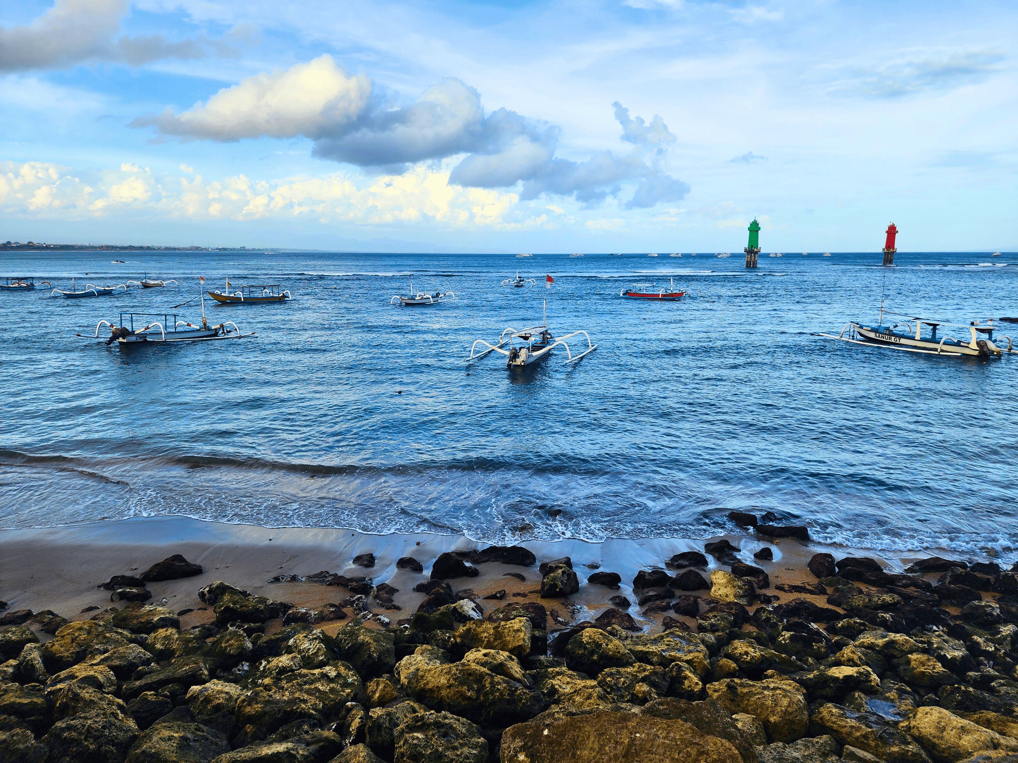 A coastal scene with boats on the water and a rocky shoreline.
