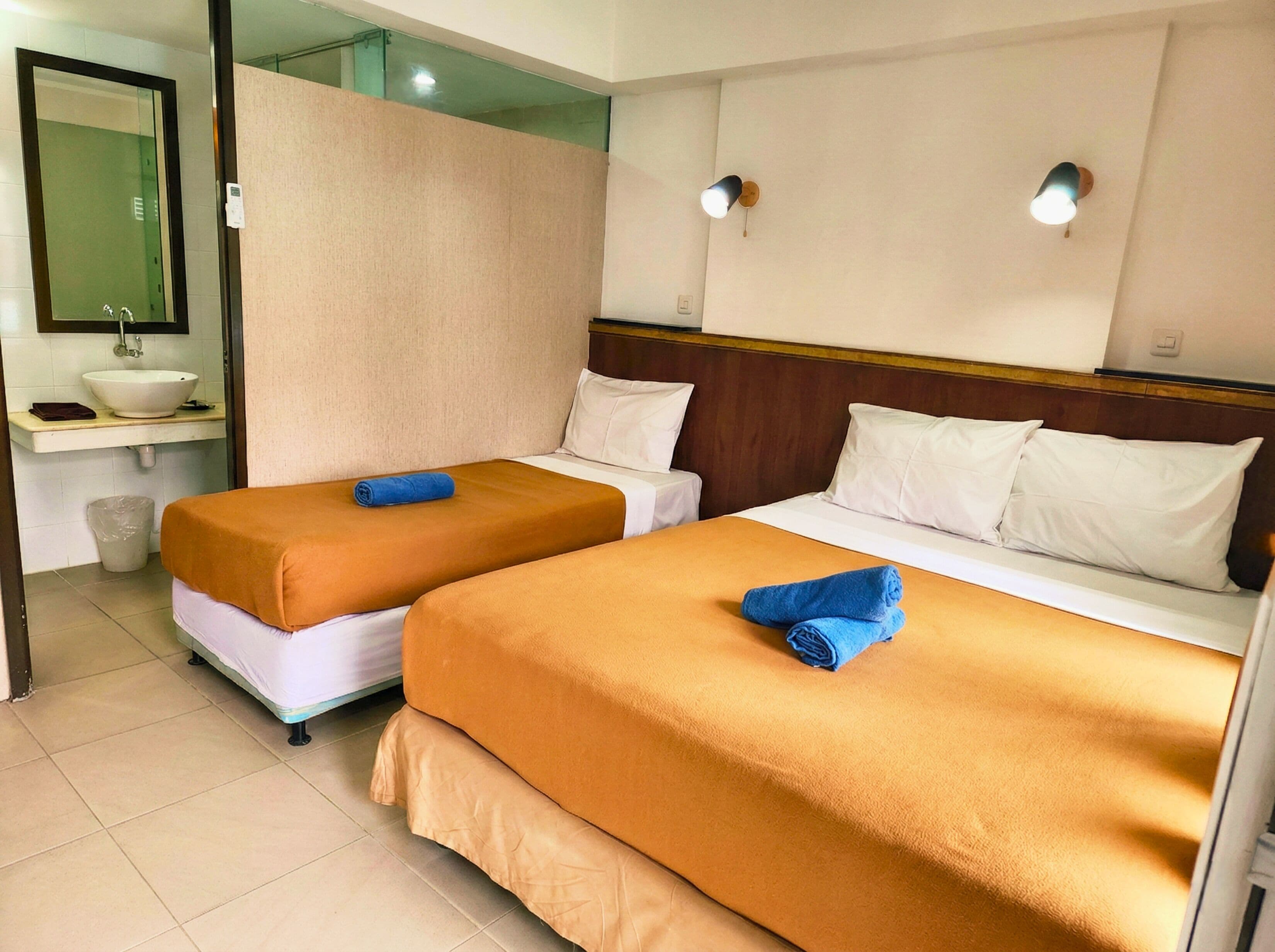 A hotel room with two beds, a bathroom, and a small sitting area.