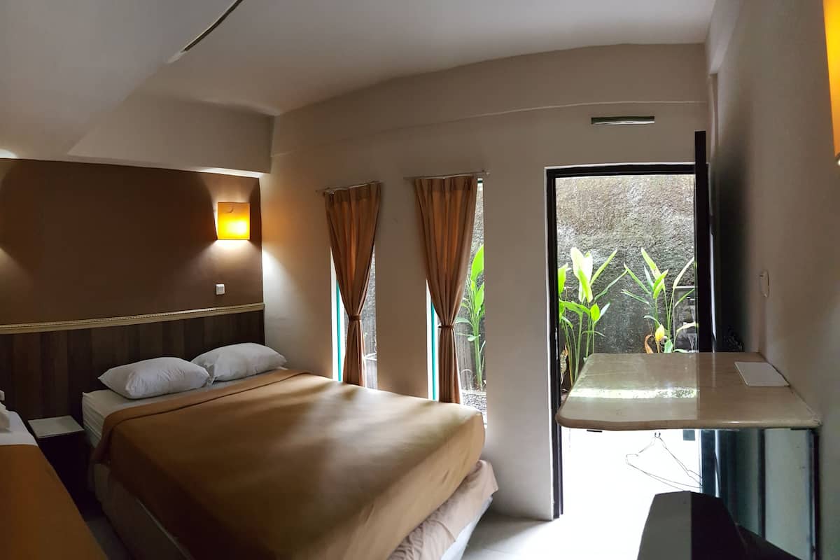 A hotel room with a bed, two bedside tables, a desk, and a window with curtains.