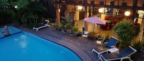Zona de piscina exterior con sillones de descanso y una mesa con sombrilla.