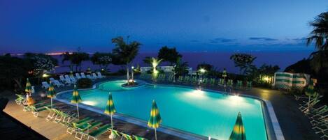 Een buitenzwembad, parasols bij het zwembad en ligstoelen