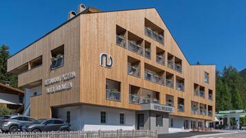 A multi-story hotel with a wooden facade, balconies with flower boxes, and a sign for 'Restaurant Pizzeria Hotel Dolomiten'.