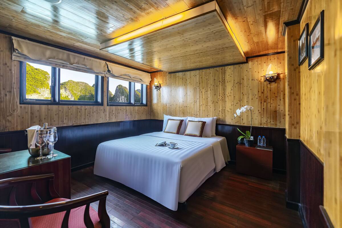 A hotel room with a large bed, a dining table, and a window with a view of mountains.