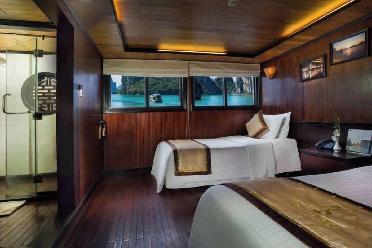 Una habitación con cama, mesita de noche, ventana con vista al agua y paneles de madera.