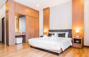 A modern hotel room with a large bed, wooden wardrobe, and bedside lamps. - Sriracha Orchid (Si Racha)