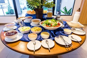 Una mesa redonda con diversos alimentos y utensilios, sobre un mantel azul.