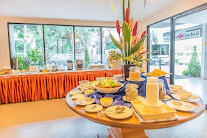 A buffet setup with various dishes and a centerpiece of red flowers. - Sriracha Orchid (Si Racha)