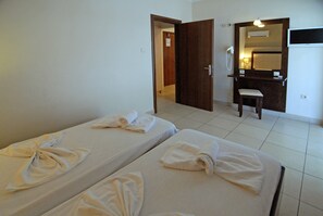 Habitació d'hotel amb dos llits, un bany amb mirall i un escriptori amb telèfon.
