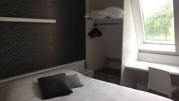 Ett välordnat hotellrum med en säng, ett skrivbord och ett fönster.