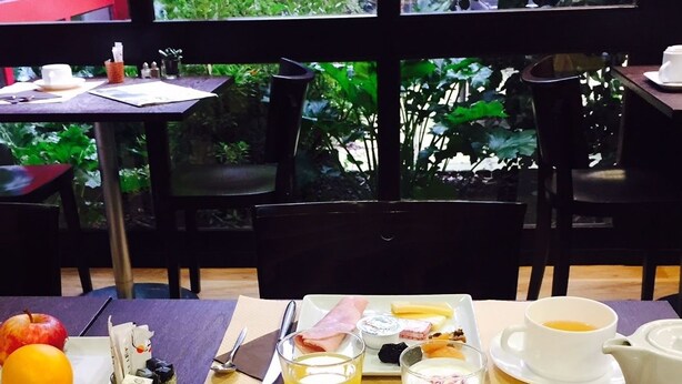 A breakfast setting with a table set for two, featuring croissants, fruit, and various breakfast items. - L'Acanthe Hôtel (Erbree)