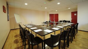 A conference room with a long table, chairs, a whiteboard, and a red door labeled "Salon." - L'Acanthe Hôtel (Erbree)