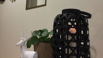 Una habitación con un espejo decorativo, un farol negro y una figurita de ciervo blanco sobre una bandeja estampada.