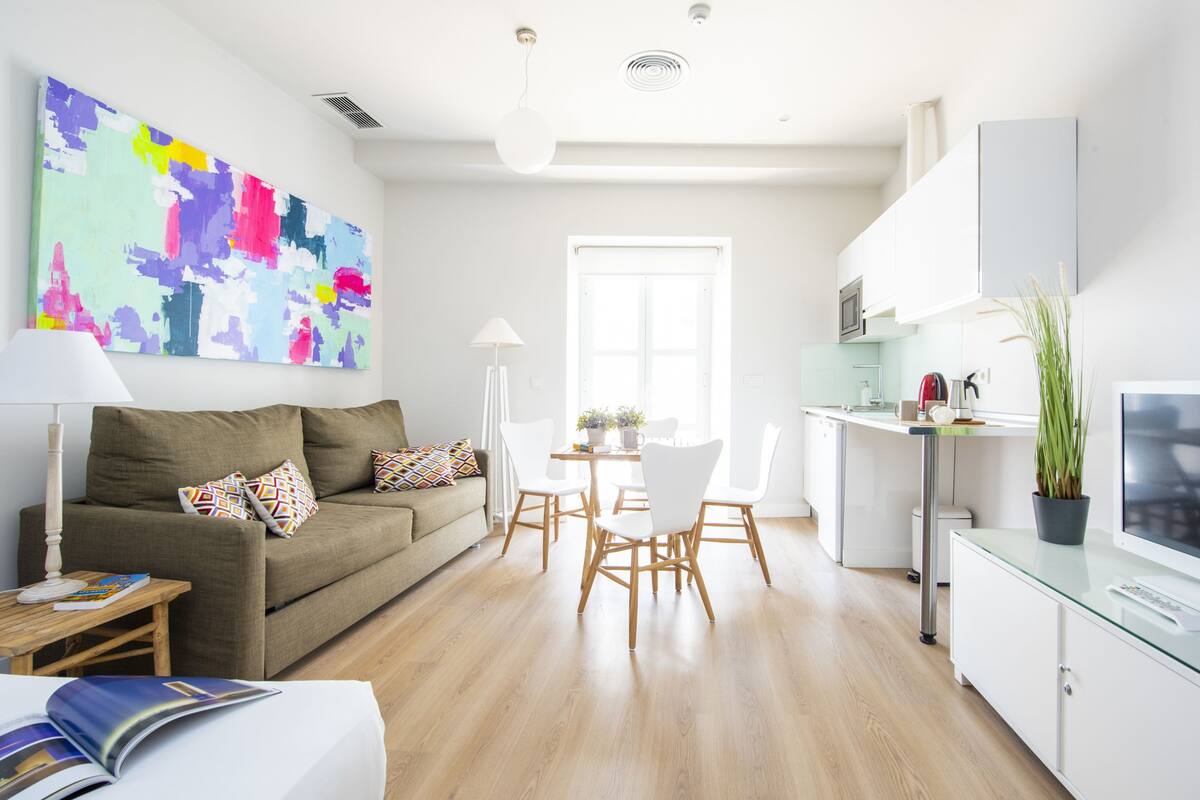 A modern living room with a sofa, coffee table, and a colorful abstract painting.