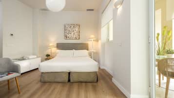 Un dormitorio moderno con una cama grande, lámparas de noche, un escritorio y una silla.