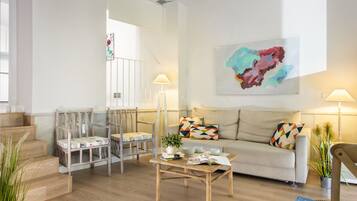 Un salon moderne avec un canapé, des fauteuils, une table basse et un escalier.