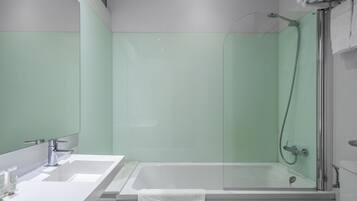 A modern bathroom with a large bathtub, a separate shower area, and a vanity with a mirror.