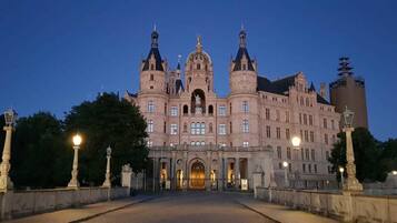 A large, historic building with a central entrance, symmetrical towers, and a prominent clock tower.