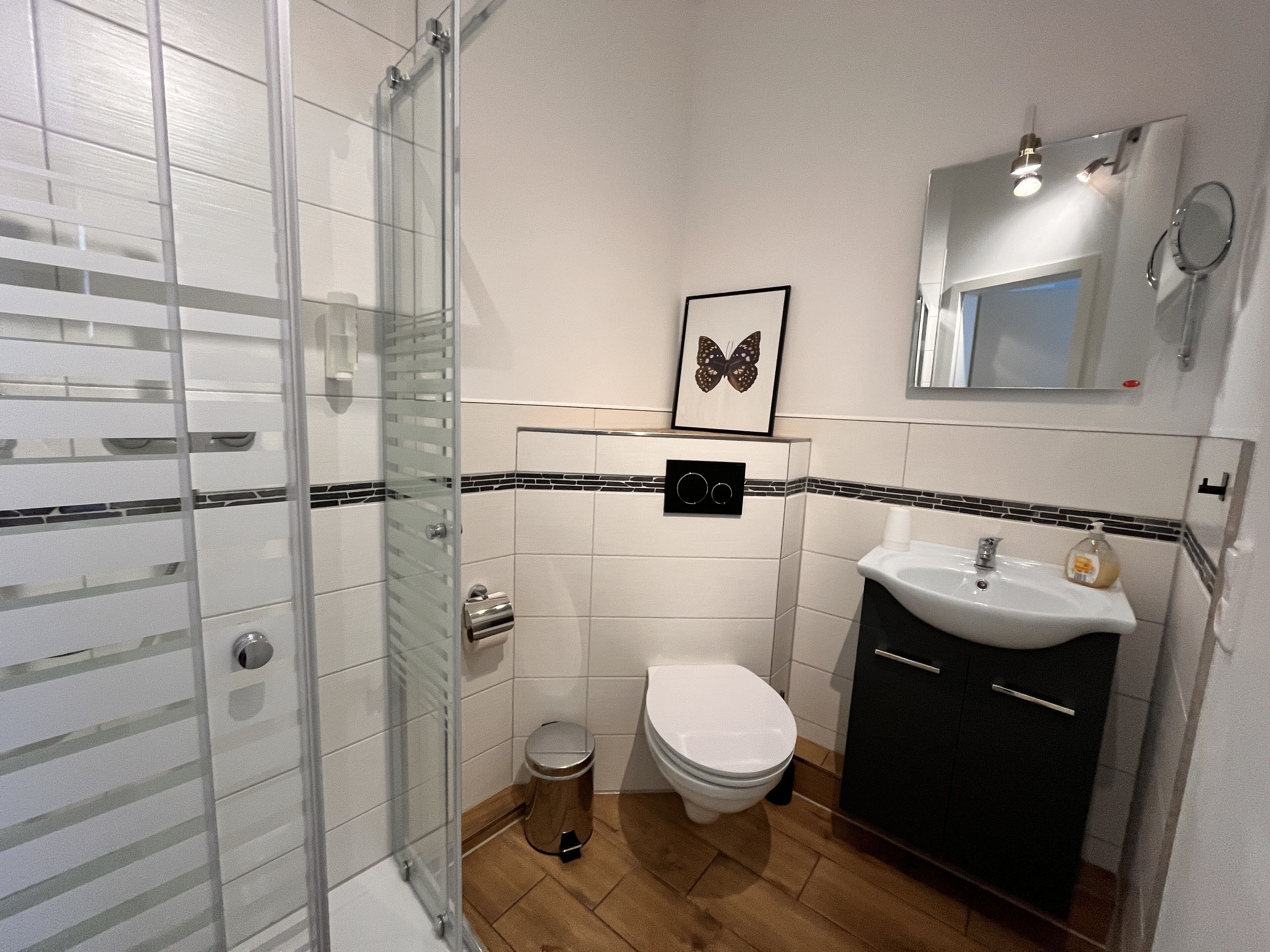 Une salle de bain avec une douche à parois de verre, des toilettes, un lavabo et un miroir.