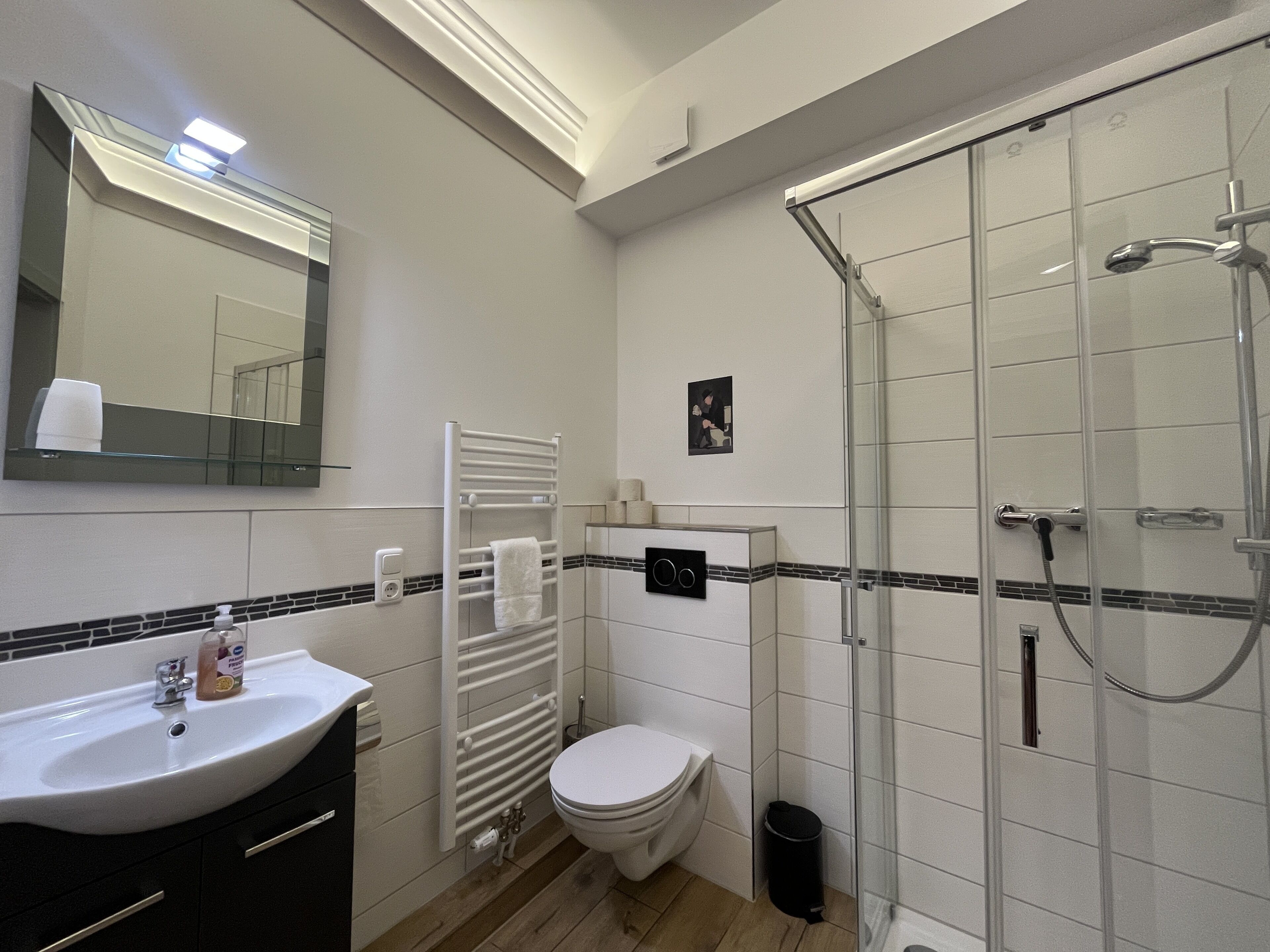 Un baño moderno con lavamanos, inodoro y ducha con mampara de vidrio.