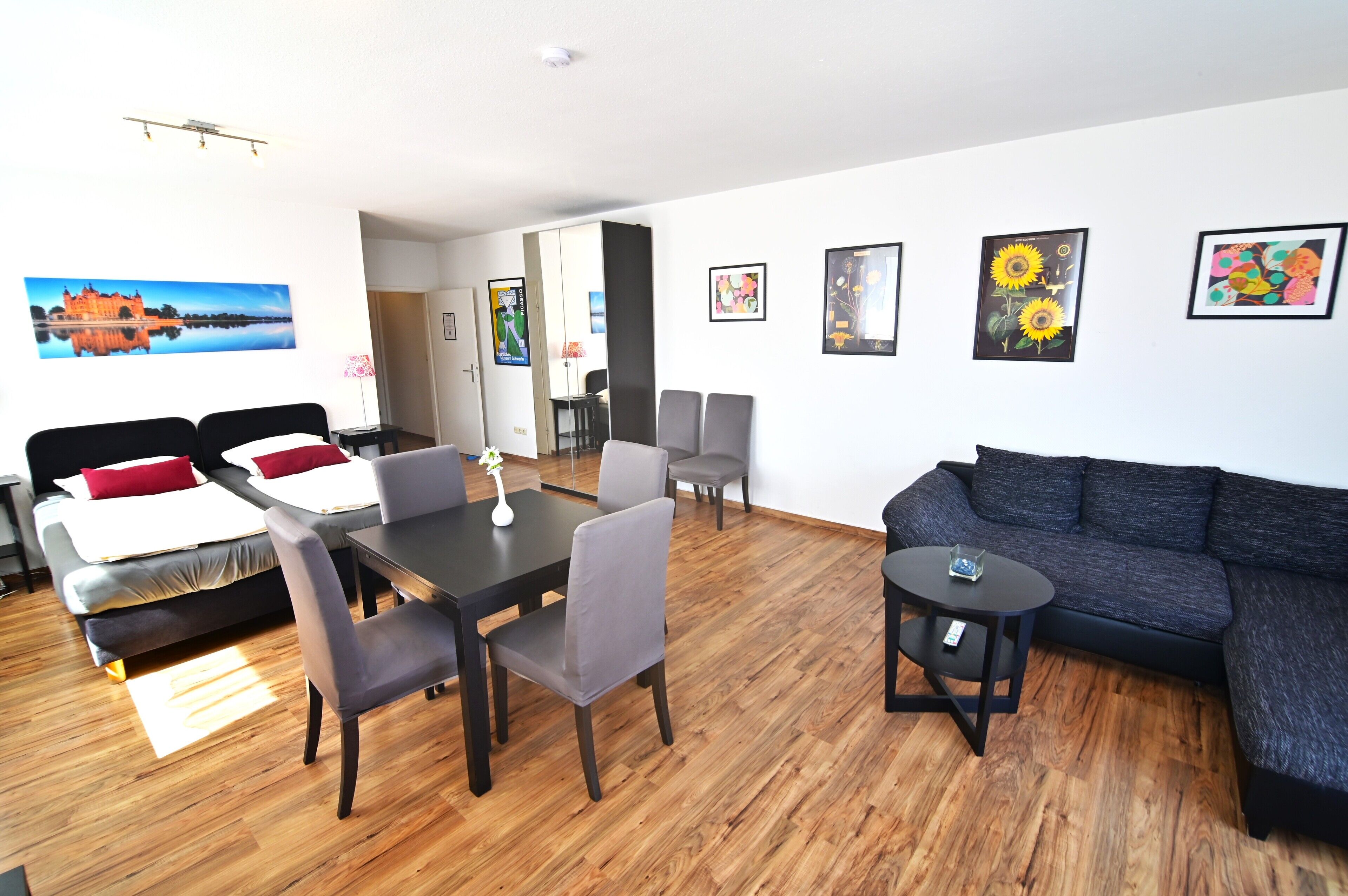 A modern living room with a sofa, dining table, chairs, and artwork on the walls.