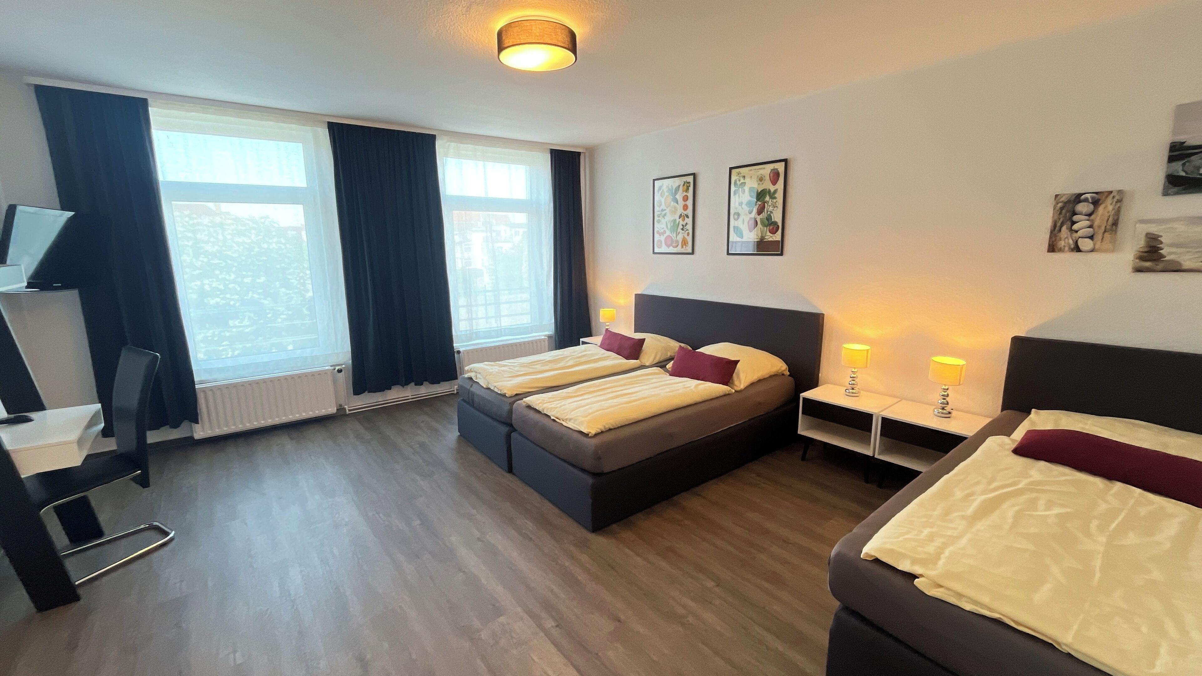 Une chambre d’hôtel avec deux lits, un bureau, une chaise et une fenêtre avec des rideaux.