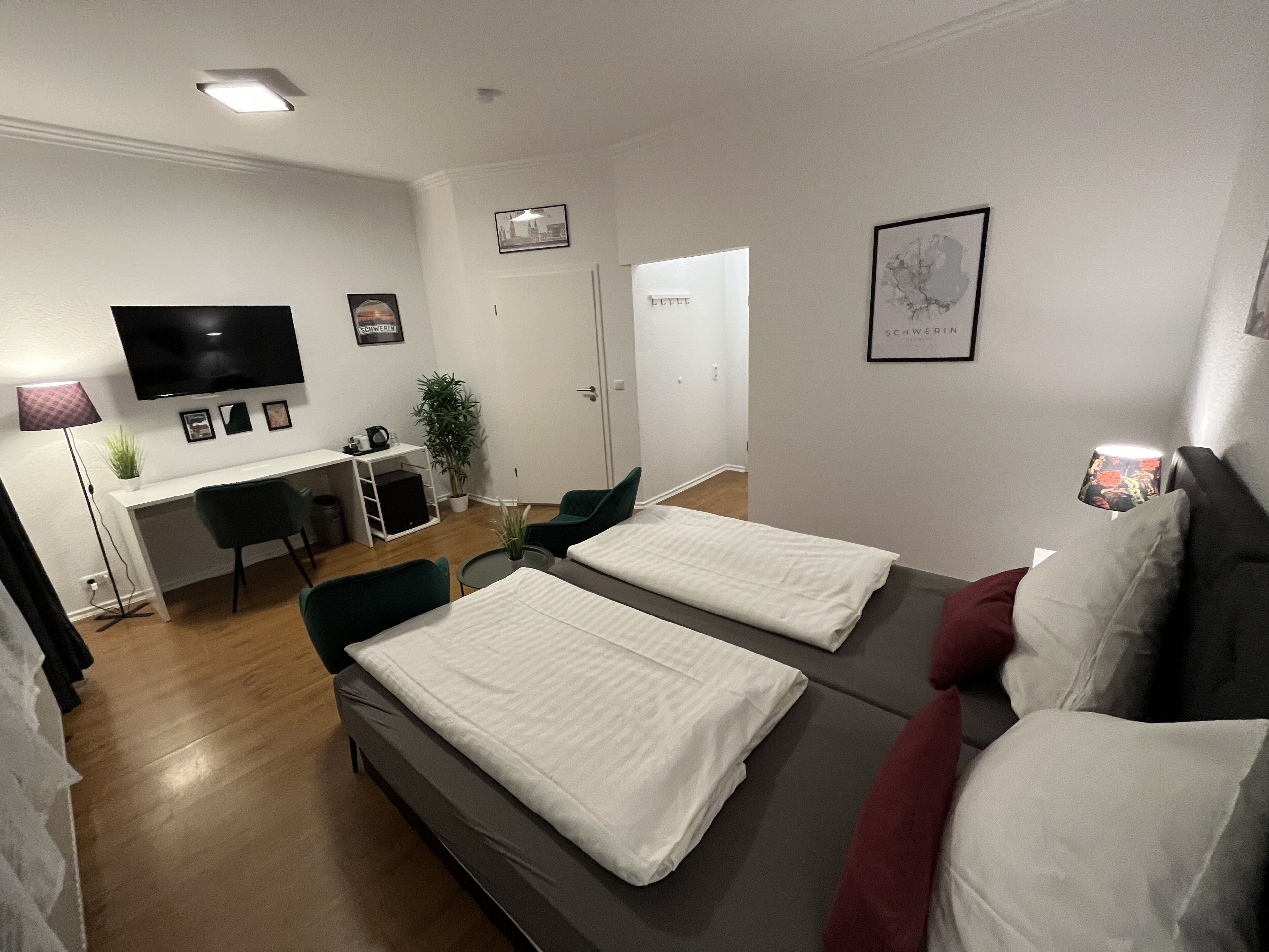 Una habitación moderna y bien iluminada con una cama, un escritorio y un televisor.