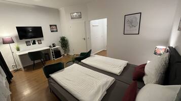 A modern, well-lit room with a bed, a desk, and a TV.