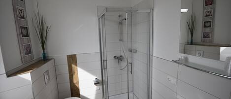 Un baño moderno con cabina de ducha de vidrio, inodoro y lavamanos.