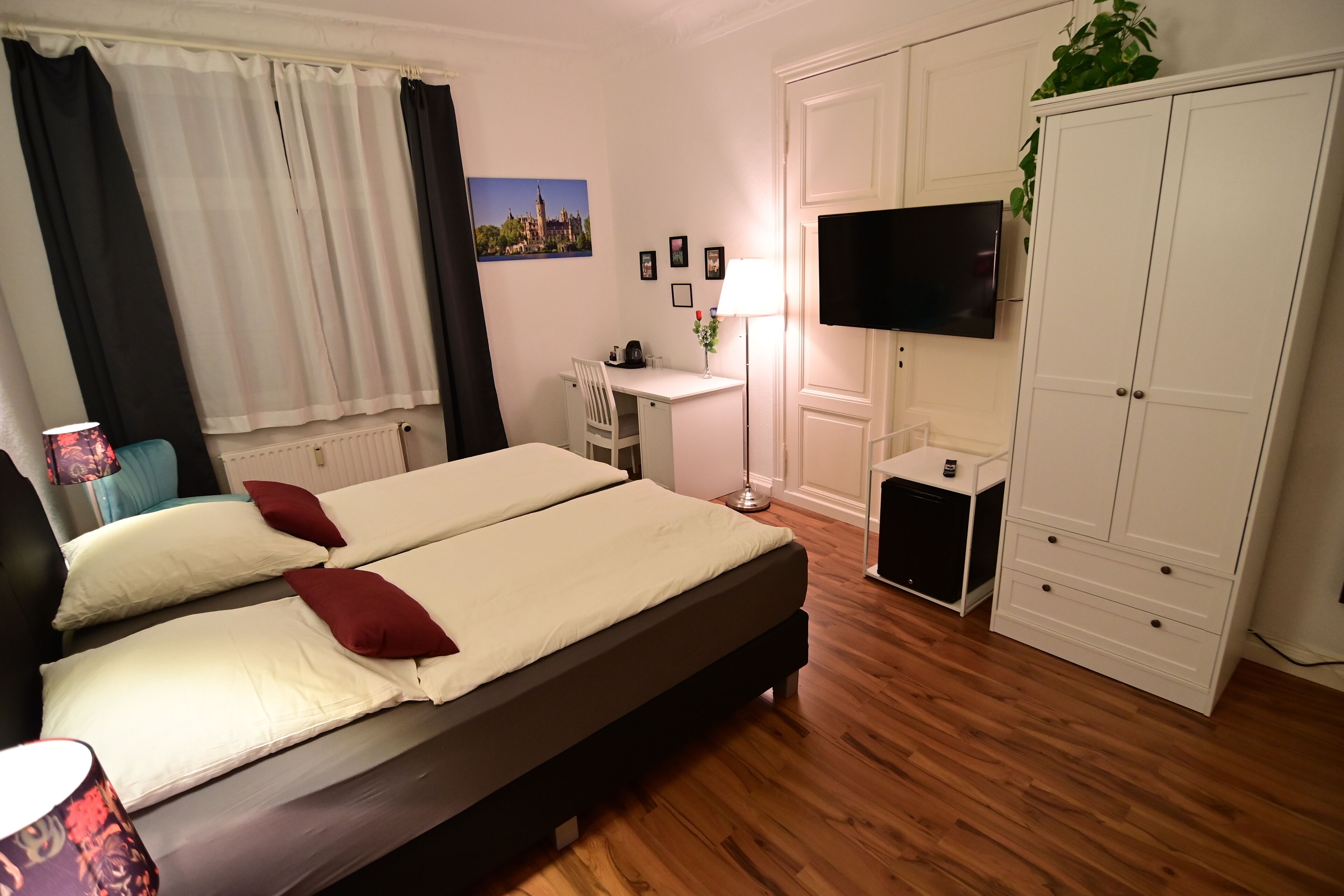 Un dormitorio con una cama doble, un escritorio, una silla, un televisor, un armario y un radiador.