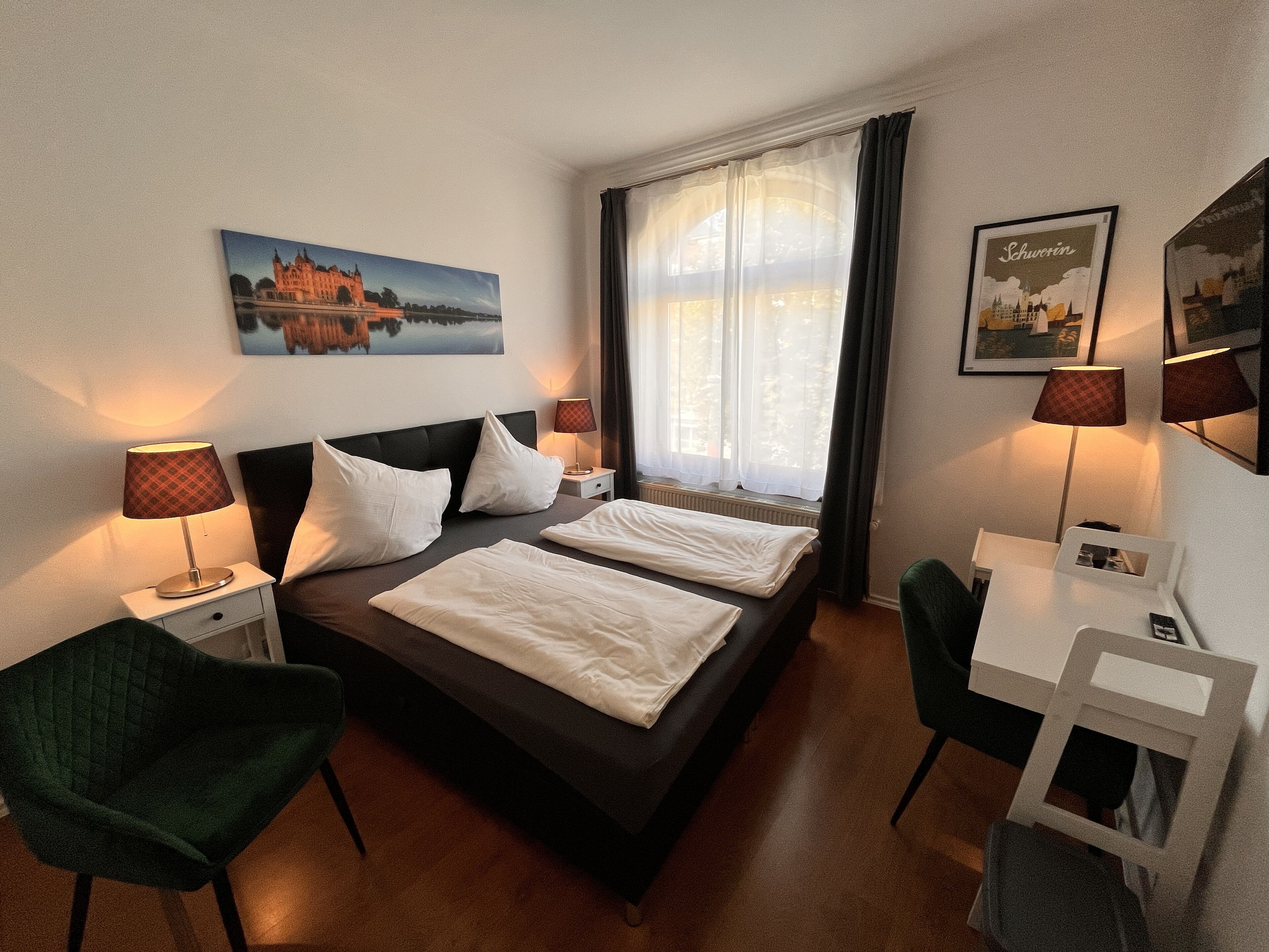 Een hotelkamer met een bed, twee nachtkastjes, een bureau en stoelen.