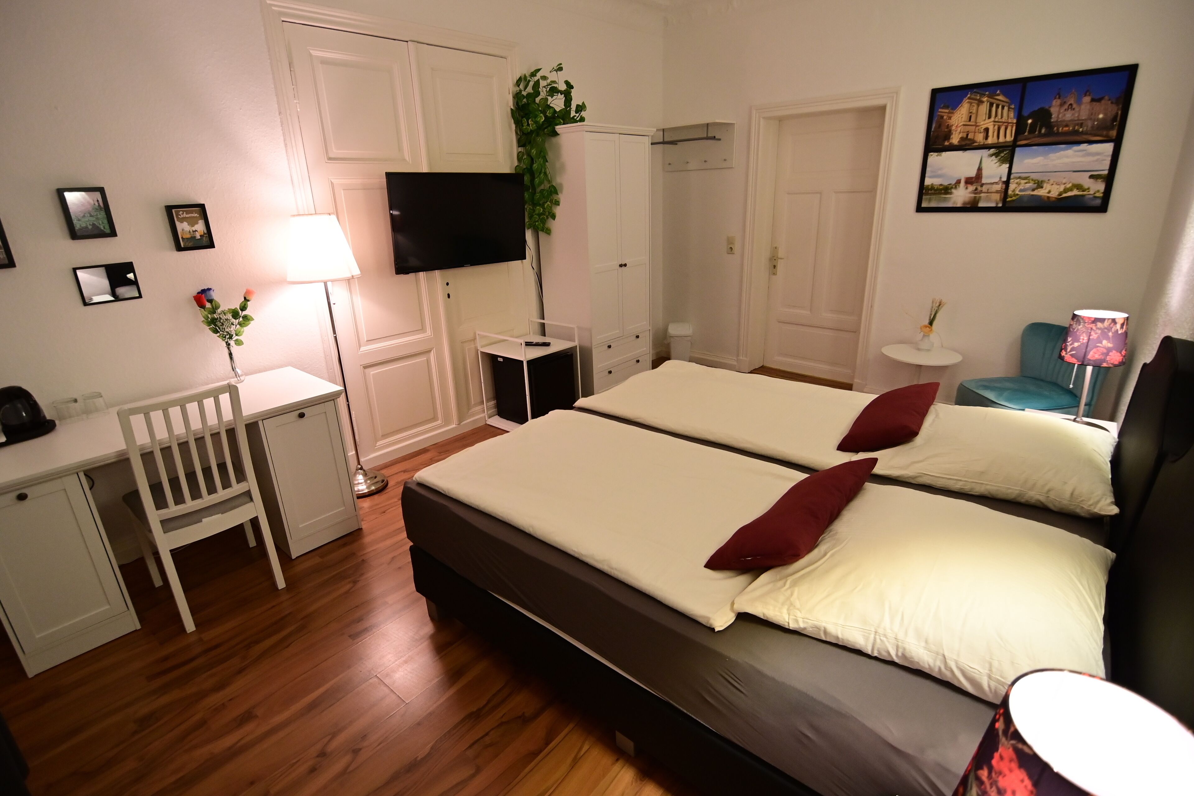 Une chambre d’hôtel équipée d’un lit, d’un bureau, d’une chaise, d’une télévision et d’une petite table avec une lampe.