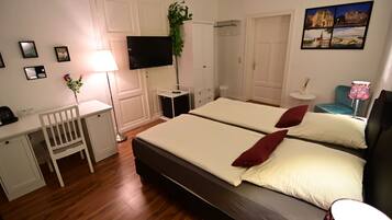 Une chambre d’hôtel équipée d’un lit, d’un bureau, d’une chaise, d’une télévision et d’une petite table avec une lampe.