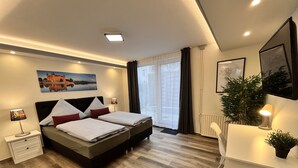Una habitación de hotel moderna con una cama grande, un escritorio y una ventana con cortinas.