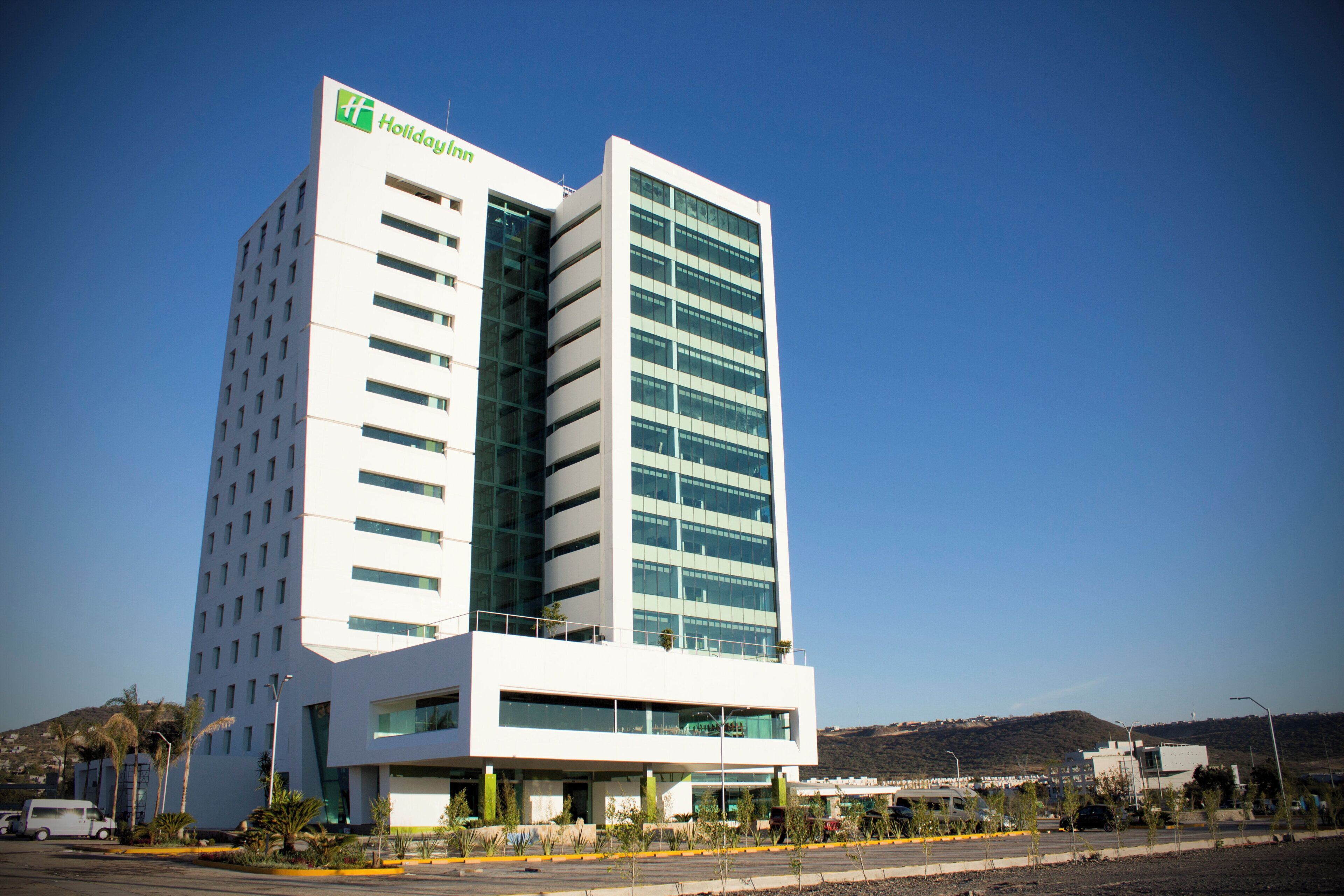 Un moderno hotel Holiday Inn con una fachada de vidrio destacada, varios pisos y un techo plano.