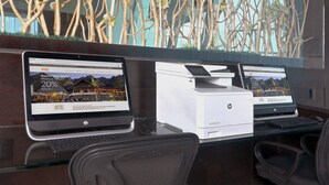 Two HP laptops on a glass desk with a printer, office chairs, and a decorative wall with branches and flowers. - Holiday Inn Queretaro Zona Krystal by IHG (Querétaro)