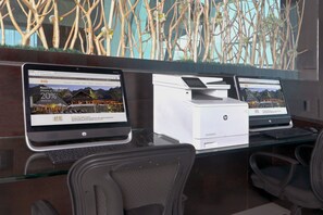 Two HP laptops on a glass desk with a printer, office chairs, and a decorative wall with branches and flowers. - Holiday Inn Queretaro Zona Krystal by IHG (Querétaro)