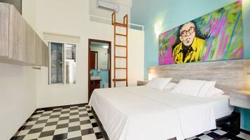 Un dormitorio con piso a cuadros, una cama con ropa de cama blanca, una escalera de madera y un cuadro colorido en la pared.