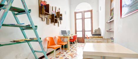 A room with a wooden table, orange chairs, a ladder, and a patterned floor.