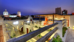 A modern hotel with a glass atrium, a bell tower, and a view of the cityscape at dusk. - Masaya Santa Marta (Santa Marta)
