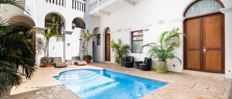 Un patio con piscina, suelo de piedra y plantas en macetas.