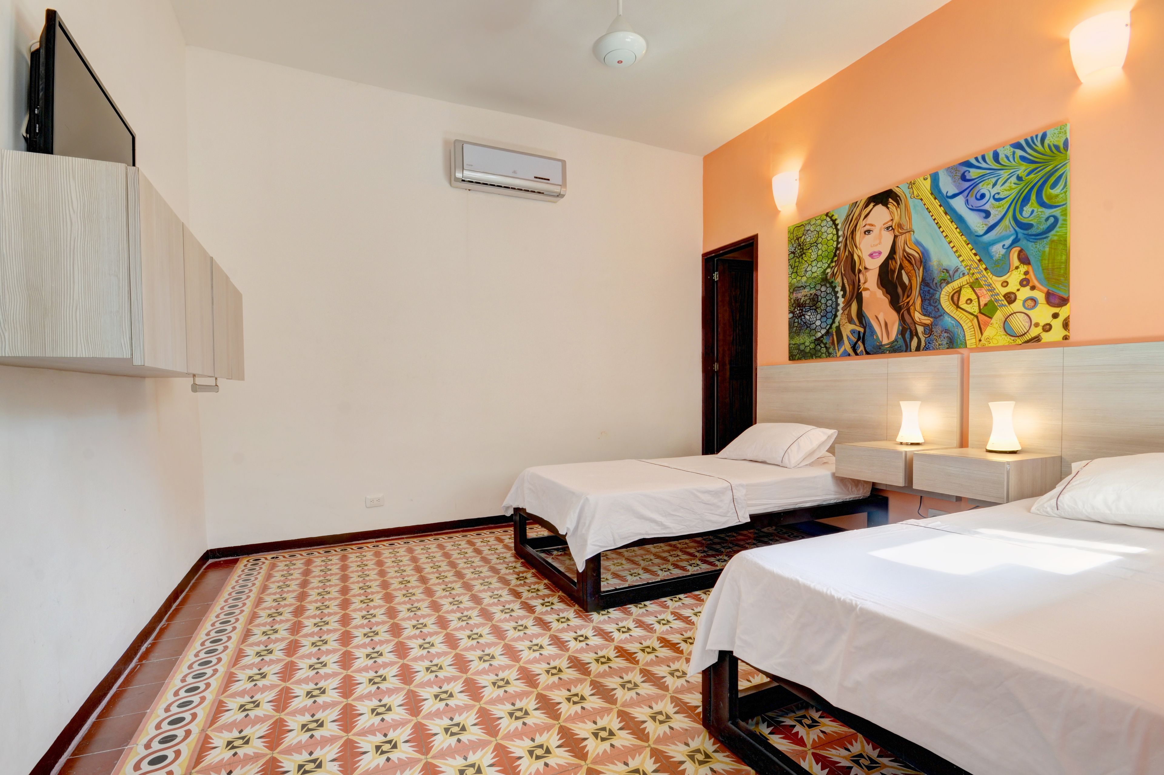 A hotel room with two beds, a painting on the wall, and a patterned floor.
