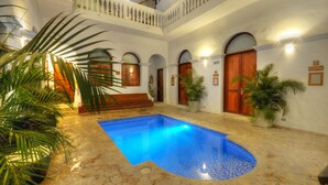 A pool area with a tiled floor, surrounded by white walls and wooden doors. - Masaya Santa Marta (Santa Marta)