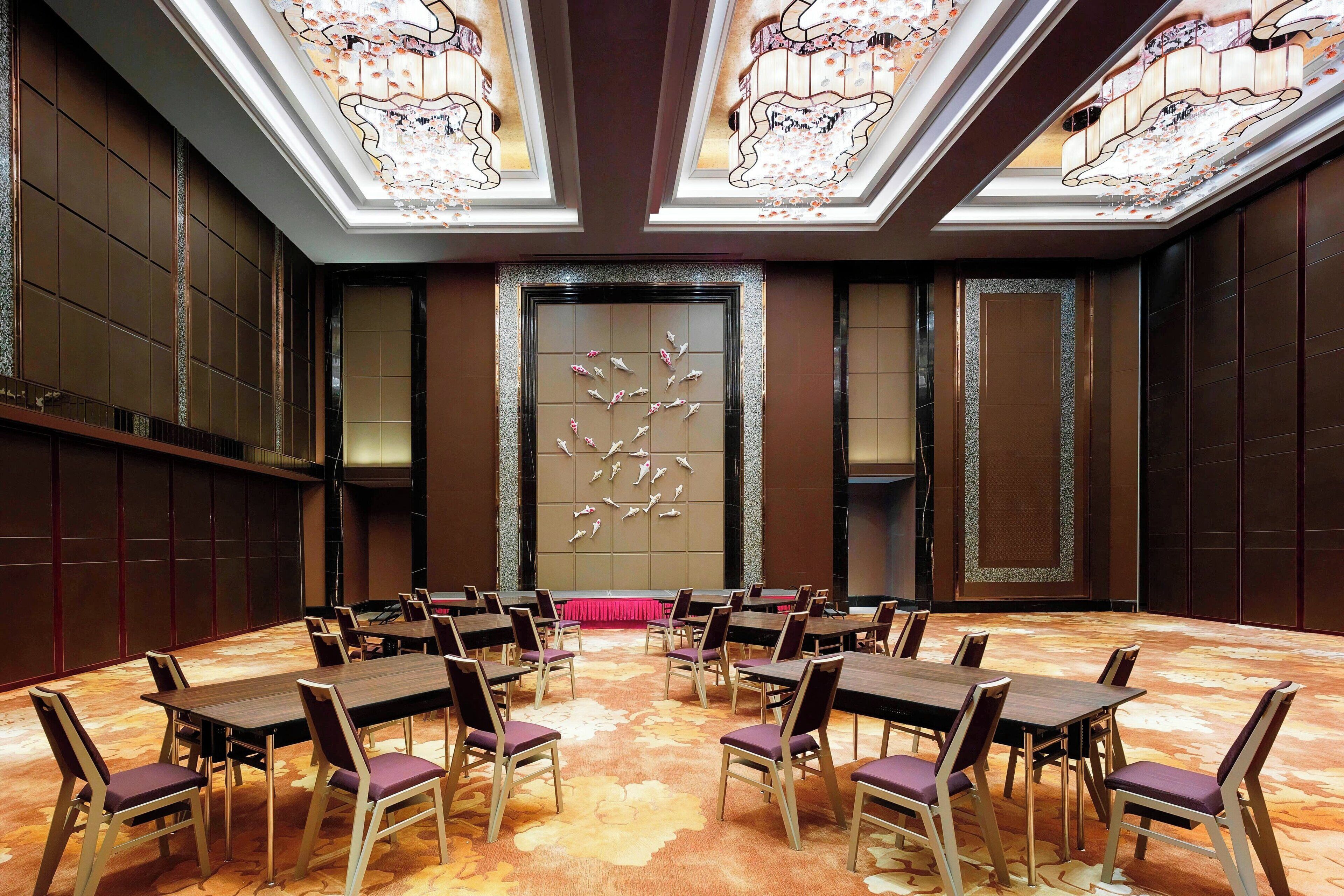 A conference room with a central table, surrounded by chairs, and a decorative wall with a floral pattern.