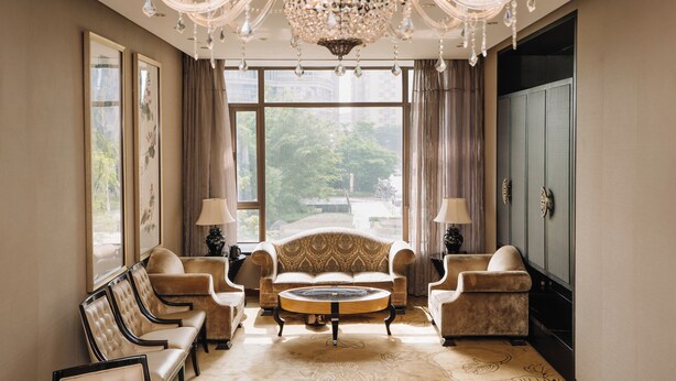 Une chambre luxueuse dotée d’une grande fenêtre, d’un lustre et d’un ensemble de meubles comprenant un canapé.