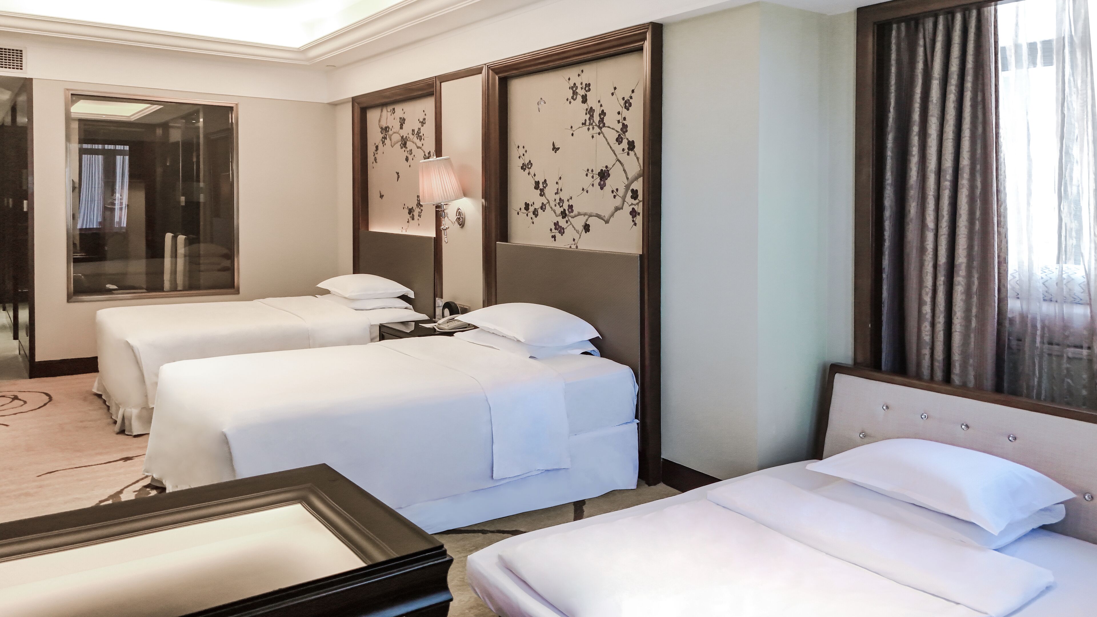 A hotel room with two beds, a large mirror, and a decorative wall panel.