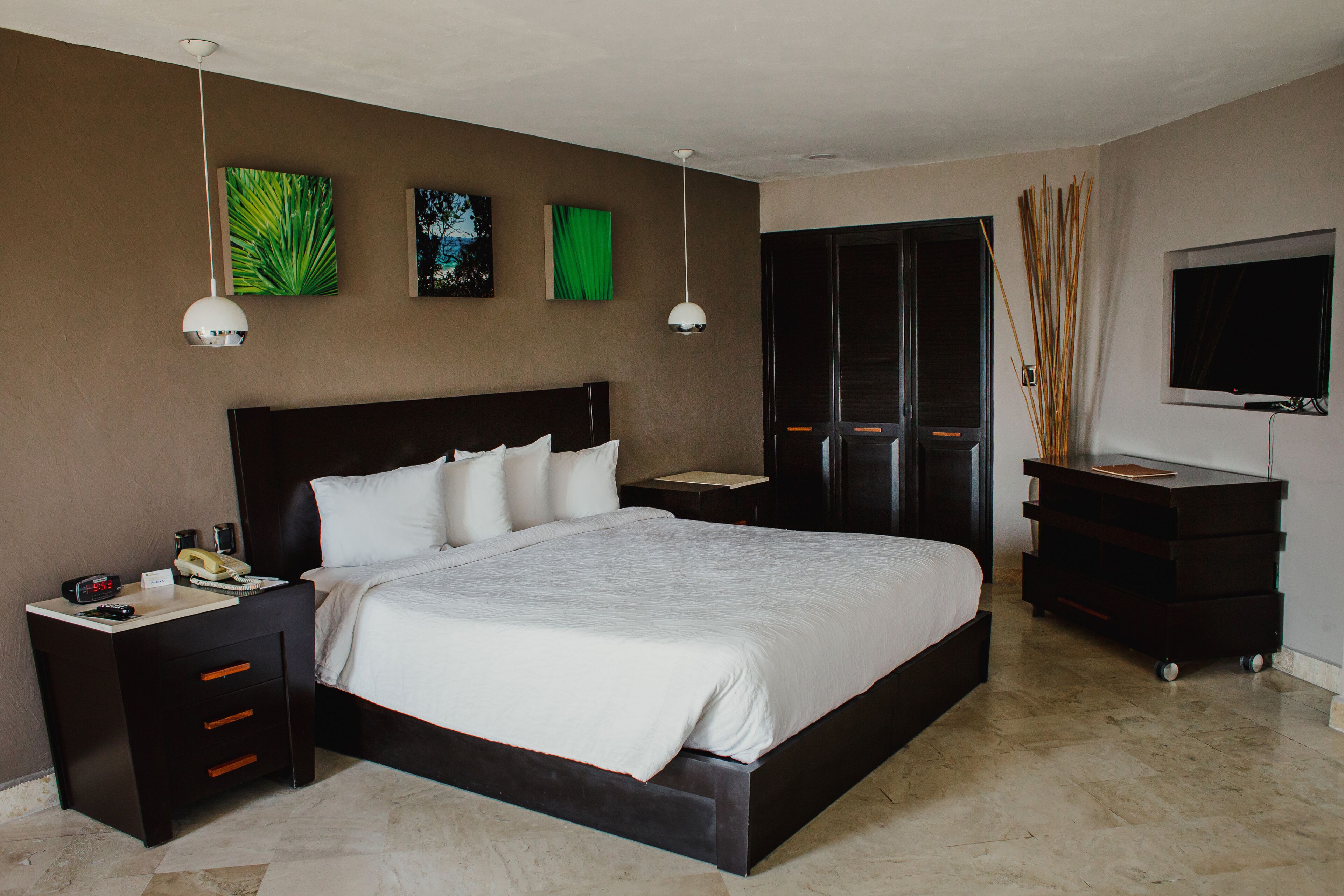 A modern hotel room with a large bed, bedside tables, a desk, and a TV.